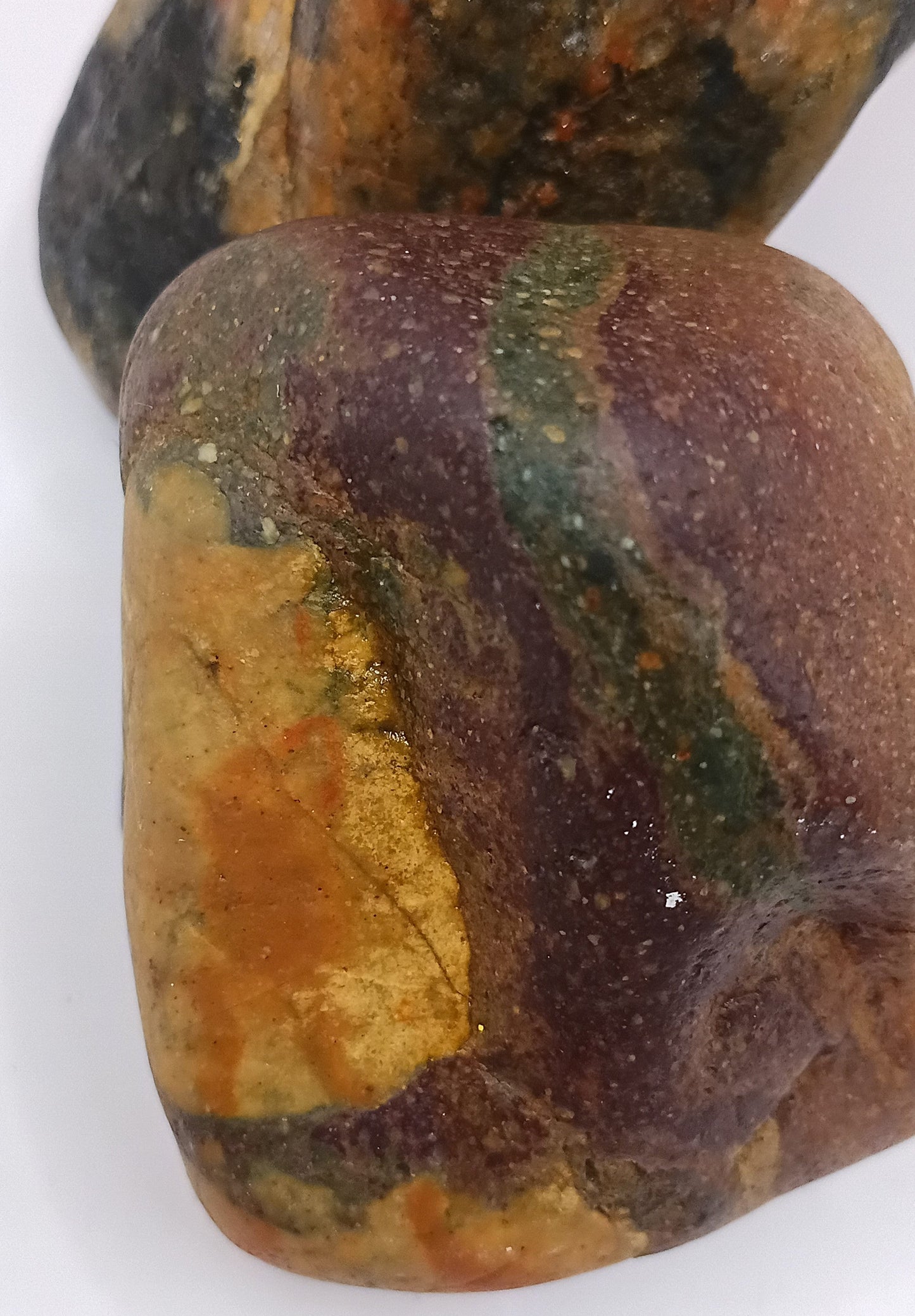 Close-up of warm amber and russet Plymouth beach stone with epidote green patches