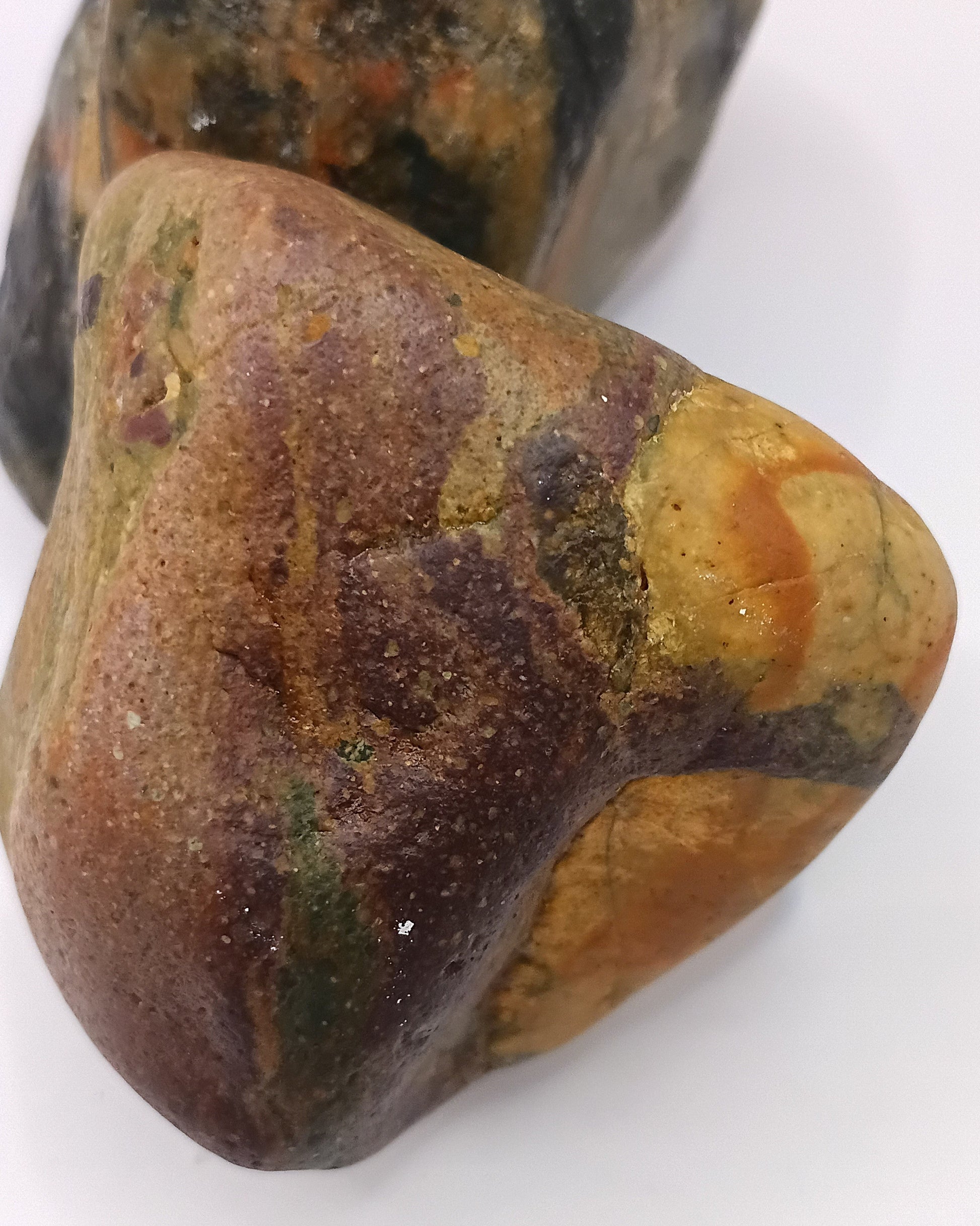 Two Plymouth beach stones side by side — warm amber and cool blue-grey tones